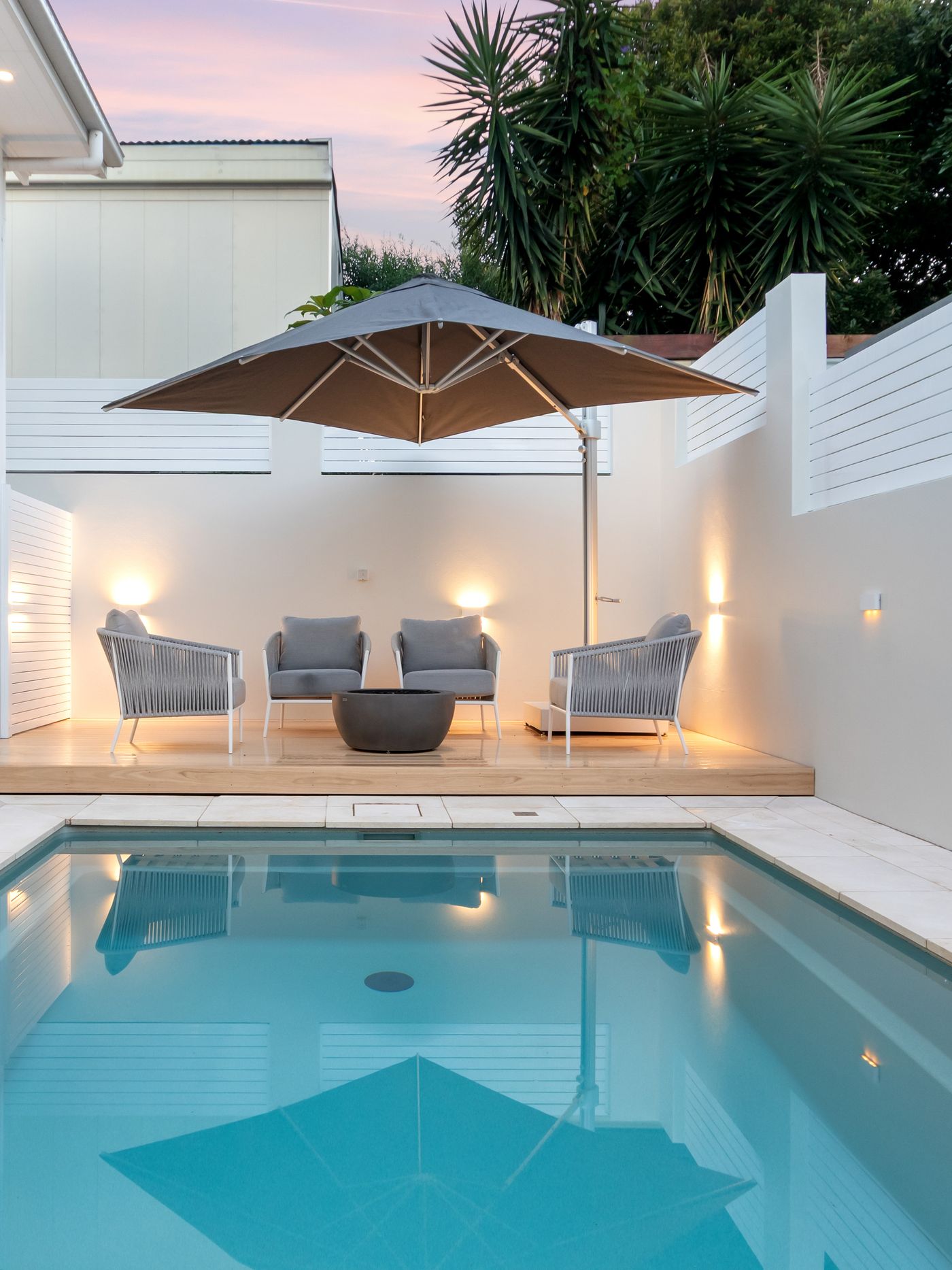The lounge deck and fire bowl beside the pool at dusk