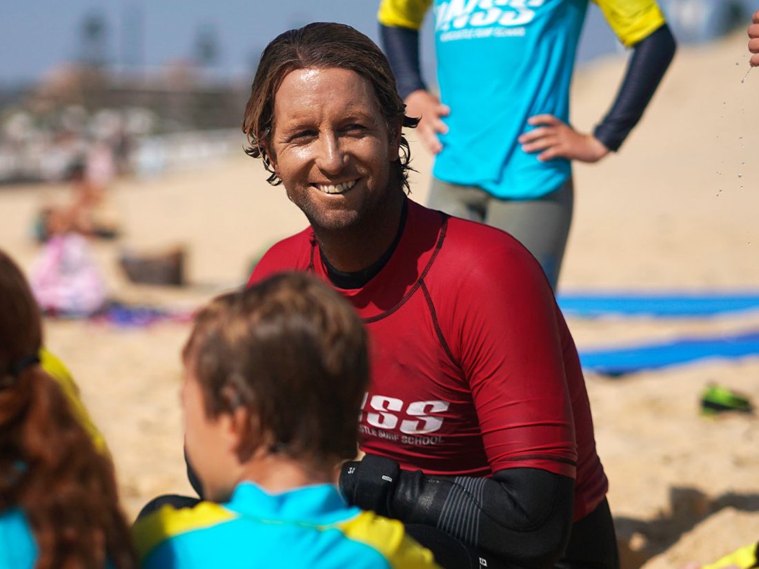 Dan Frodsham of Newcastle Surf School on the beach with a lesson